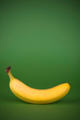 One single banana. Studio photo isolated on green background.