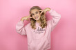 © Irene - Young beautiful child girl standing over isolated pink background Doing peace symbol with fingers over face, smiling cheerful showing victory