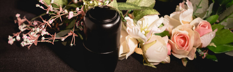 Wall Mural - Rose bouquet and urn with ashes on black funeral concept, banner
