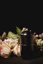 Rose Bouquet And Urn With Ashes On Black Background, Funeral 