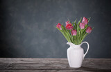 Fototapeta Tulipany - beautiful tulips in white jug on dark background