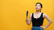 Annoyed overheated asian woman waving fan. Isolated on yellow background. High quality photo