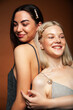 © iordani - two pretty diverse girls happy posing together: blond and brunette on brown background, lifestyle people concept