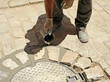 Albañil vertiendo cemento líquido en las llagas del adoquinado. Pavimentación de una calle a la manera tradicional con adoquines en Sevilla, España