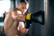 © goami - close up of muscular boxer male workout and training with punching bag in gym