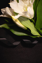 Wall Mural - closeup of lily bouquet and ribbon on black , funeral concept