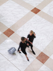 Blurred Businesswomen Walking With Suitcase On Tiled Floor