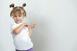 cute baby girl points to the background behind herself. mock up for your design. space for text and copy space