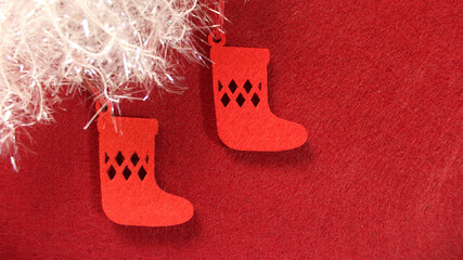 Christmas decoration: red Christmas tree toy made of felt in the form of a Christmas sock for gifts. Two socks on a red background with white shiny snow. Copy space.