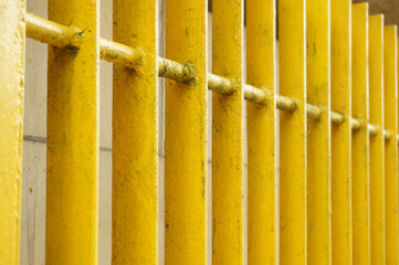 Wall Mural - Closeup shot of a yellow painted metal fence