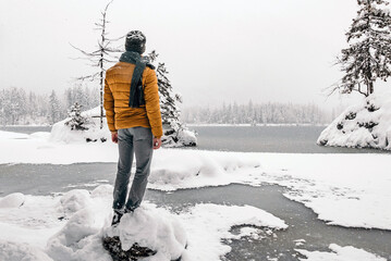 Wall Mural - Back view of a young male enjoying the view of a frozen lake