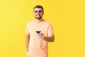 Wall Mural - Handsome man with stylish sunglasses and cocktail on color background