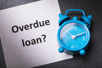 Alarm clock and note with text on the table. Overdue loan concept