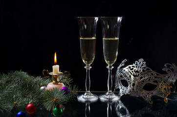 Canvas Print - Two glasses of champagne, a burning candle? a carnival mask, a spruce branch and Christmas decorations on a dark background.