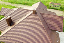 Detail Of A House Roof Surface Covered With Brown Metal Tile Sheets.