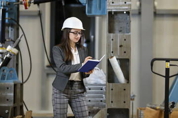 Wall Mural - Portrait of a female factory manager in a business suit holding notebook, controlling the work process in the manufacturer.	