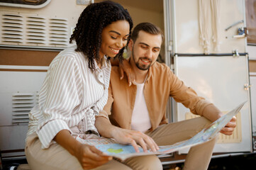 Couple looking on map near rv, camping in trailer