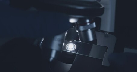 Wall Mural - close-up shot of sample slide and microscope with metal lens at laboratory.