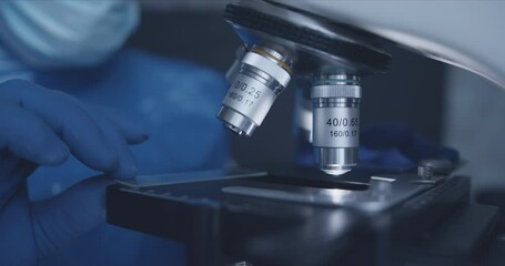 Wall Mural - close-up shot of sample slide and microscope with metal lens at laboratory.