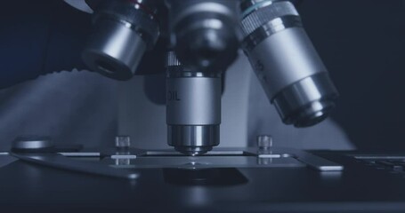 Wall Mural - close-up shot of sample slide and microscope with metal lens at laboratory.