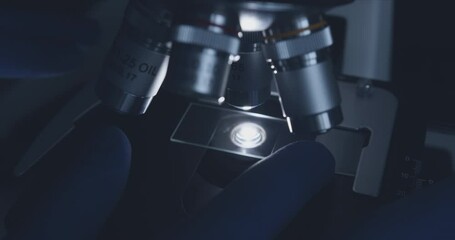 Wall Mural - close-up shot of sample slide and microscope with metal lens at laboratory.