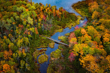 Beautiful Travel Aerial Looking Down At Carp River Where It Connects With Lake Of The Clouds On Top Of Porcupine Mountain In Upper Michigan With Gorgeous Colorful Fall Leaf Foliage In Autumn.