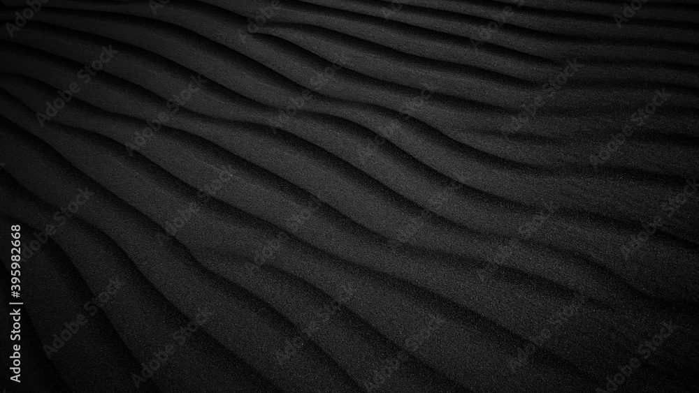 Black Sand dune. Black Sand beach macro photography. Background, texture, wave pattern of oceanic sand on the beach, black. Texture of beach sand. Black beach.