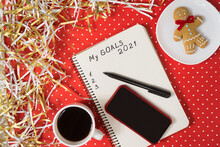 Phrase My Goals 2021 In A Notebook, Black Pen And Smart Phone. Gingerbread And Coffee On Red Background.