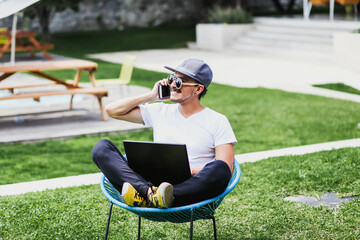 latin man using his mobile phone and computer in a home terrace in Mexico city