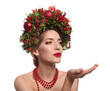 Beautiful young woman with Christmas wreath blowing kiss on white background