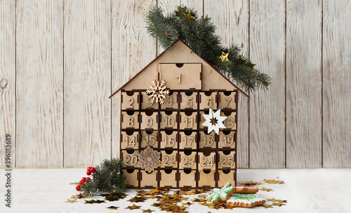 Fotomural Wooden house shaped advent calendar, Christmas cookies and festive decor on whit