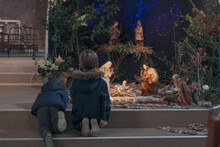 Children Look At Christmas Creche With Joseph Mary And Small Jesus In A Crib