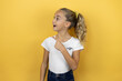 © Irene - Young beautiful child girl standing over isolated yellow background pointing with hand and finger to the side with surprised expression