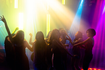 Silhouette image of people dance in disco night club to music from DJ on stage . New year night party and nightlife concept .