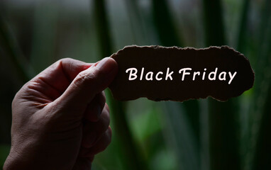 Wall Mural - Black Friday Text On Hands Holding Torn Paper With Blurred Dark Background