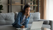 © fizkes - Wide banner panorama view of serious millennial female student on headphones study distant on laptop from home. Focused young woman in earphones look at computer screen working online on device.