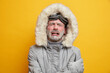 © WHstudio Leushin N - Stressed cold man cries from despair has displeased face expression frozen face covered with hoarfrost wears grey jacket isolated over yellow background spends long time during winter storm.