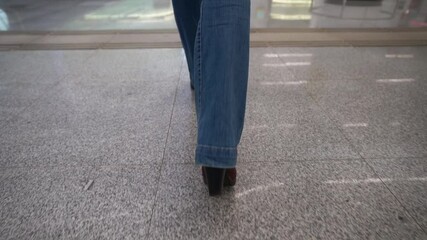 woman is walking over tiled floor in metro station or other public place in city, closeup of feet