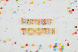 Sweet tooth words made of delicious homemade cookies covered with sprinkles, view from above