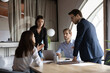 © fizkes - Multicultural group of millennial colleagues working in team having talk conversation discussion on formal meeting briefing, proposing financial strategy, comparing statistic data, analyzing results