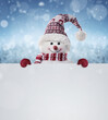 © rangizzz - Happy snowman in the winter scenery behind the blank advertising banner with copy space