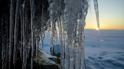 Wall Mural - icicles on the shore of a frozen lake at sunset. timelapse