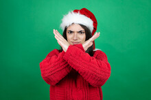 Young Beautiful Woman Wearing Christmas Santa Hat Over Isolated Green Background Rejection Expression Crossing Arms Doing Negative Sign, Angry Face