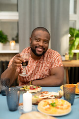 Wall Mural - Happy young African man cheering up with glass of red wine in front of camera