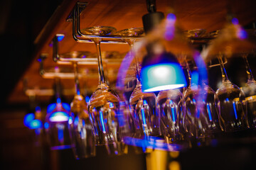 Sticker - Closeup of transparent drinking glasses hung from the metal pole in the bar