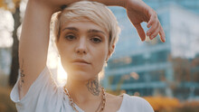 Portrait Of Beautiful Young Short Haired Blond Woman In The Park During The Sunset. High Quality Photo