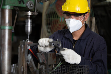 male technician or factory worker wearing face mask for protect virus, using calipers measures in factory