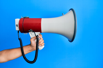 Canvas Print - Hand of hispanic man holding megaphone over isolated blue background.