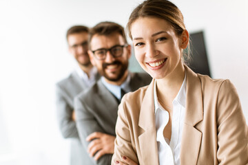 Wall Mural - Smiling young business woman standing with group of corporate colleagues in a row together