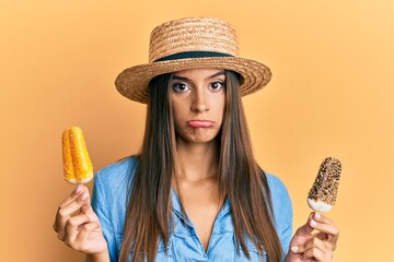 Wall Mural - Young hispanic woman wearing summer style holding ice cream depressed and worry for distress, crying angry and afraid. sad expression.